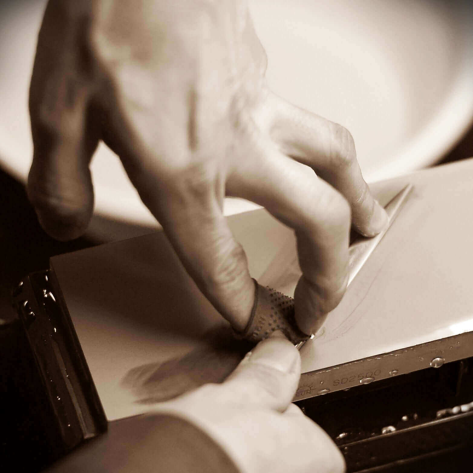 Master blade sharpener honing professional hair cutting scissors on a whetstone – traditional Japanese sharpening technique for precision edge maintenance and superior cutting performance.