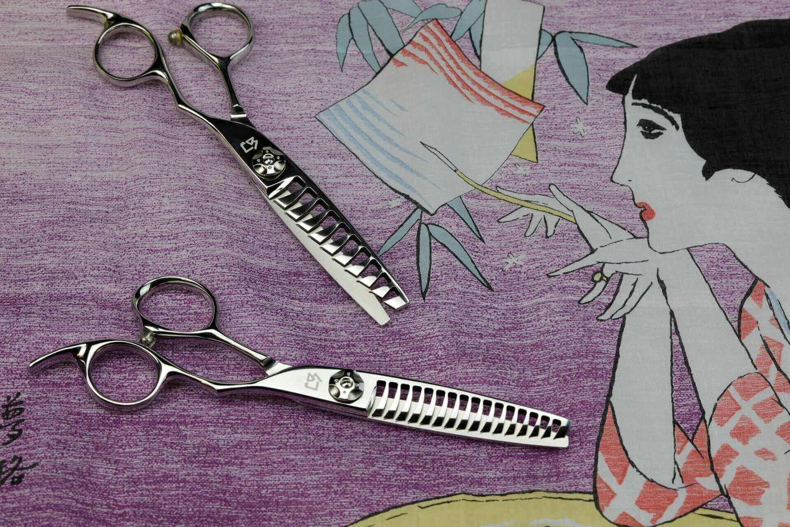 Close-up of high-end Japanese texturizing shears for hairstylists, displayed on artistic purple fabric with illustrated woman—perfect for salon styling and texture blending.