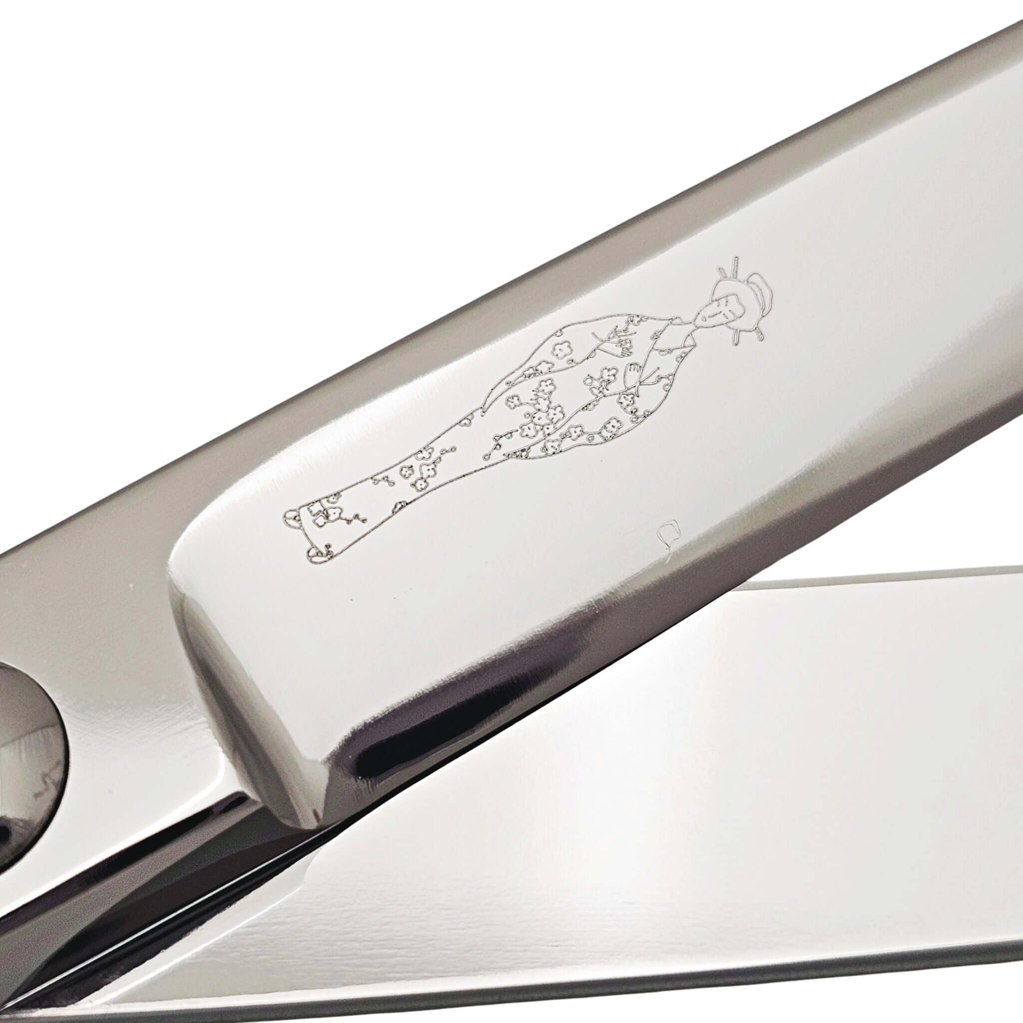 Close-up of a barber shear blade with engraved Japanese lady design on a white background