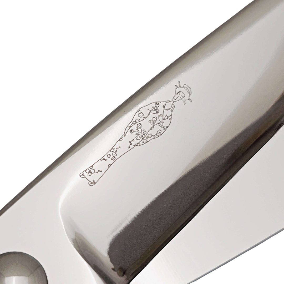 Close-up of a hair scissor blade with an engraved Japanese lady design on a white background