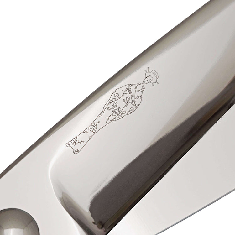 Close-up of a hair scissor blade with an engraved Japanese lady design on a white background