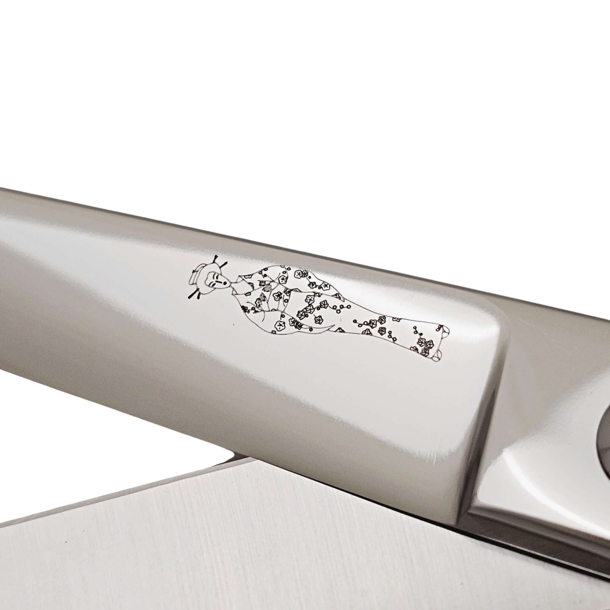 Close-up of a hair scissor blade with engraved Japanese lady wearing a kimono design on a white background