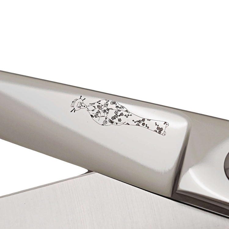 Close-up of a hair scissor blade with engraved Japanese lady wearing a kimono design on a white background