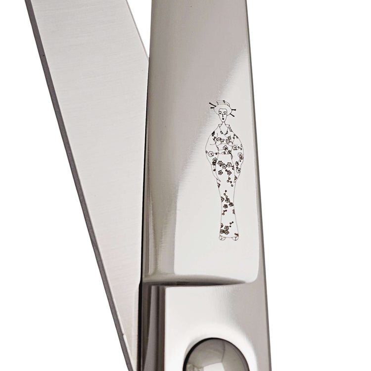 Close-up of hair scissors blades with decorative Japanese lady wearing a kimono engraving on a white background