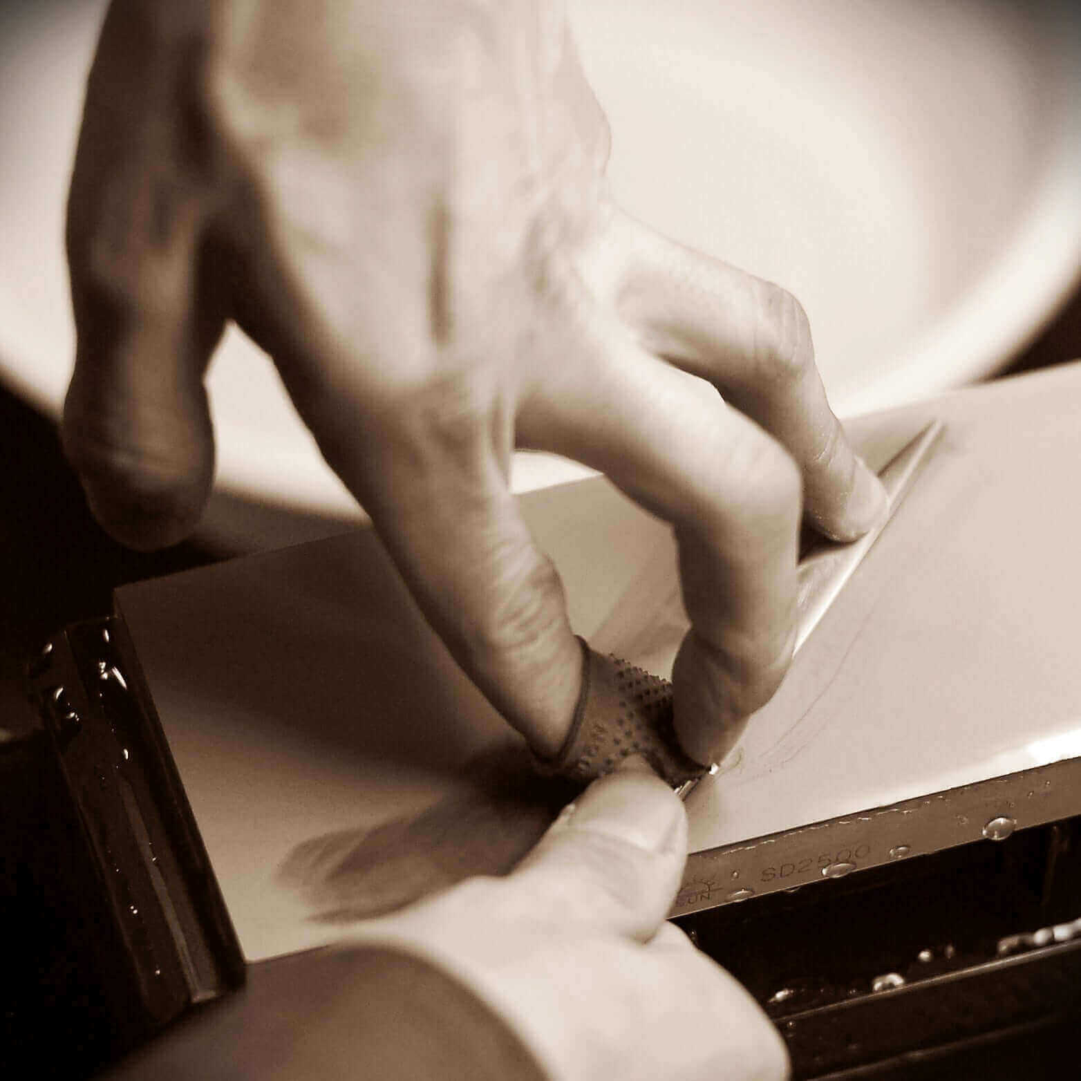 Master blade sharpener honing professional hair cutting scissors on a whetstone – traditional Japanese sharpening technique for precision edge maintenance and superior cutting performance.