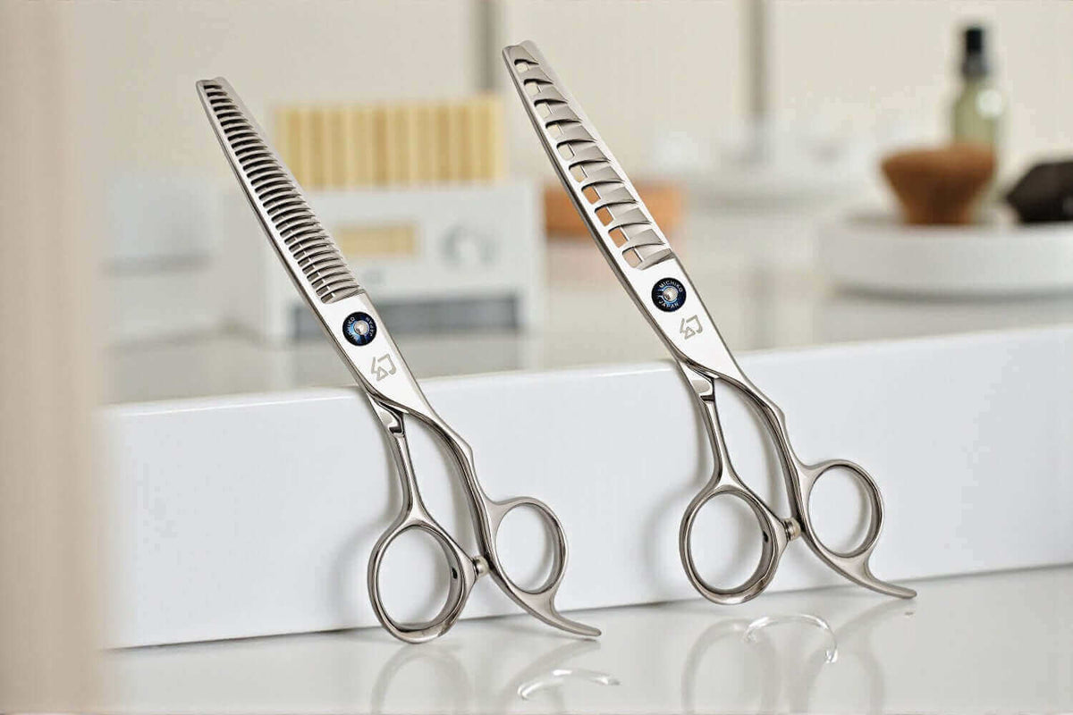 Two pairs of silver professional hair scissors (one texturizing and one thinning shear) with blue jewel accents, balanced on a white salon station.