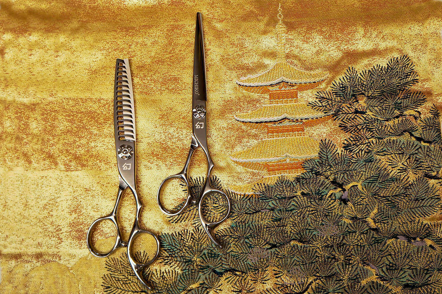 Two pair of hair cutting scissors on a golden Japanese fabric.