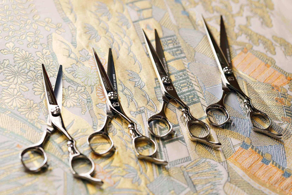Various sizes of hair cutting scissors displayed in an open position against an oriental-themed background.