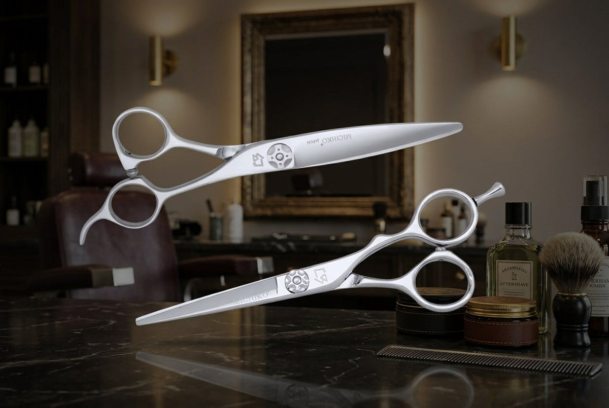 Two pairs of silver scissors rest on a dark, reflective barbershop counter against a softly blurred, sophisticated salon background.