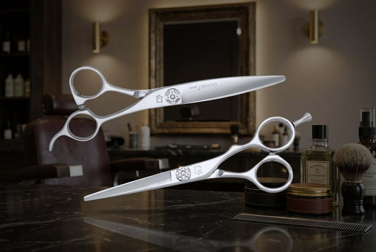 Two pairs of silver scissors rest on a dark, reflective barbershop counter against a softly blurred, sophisticated salon background.