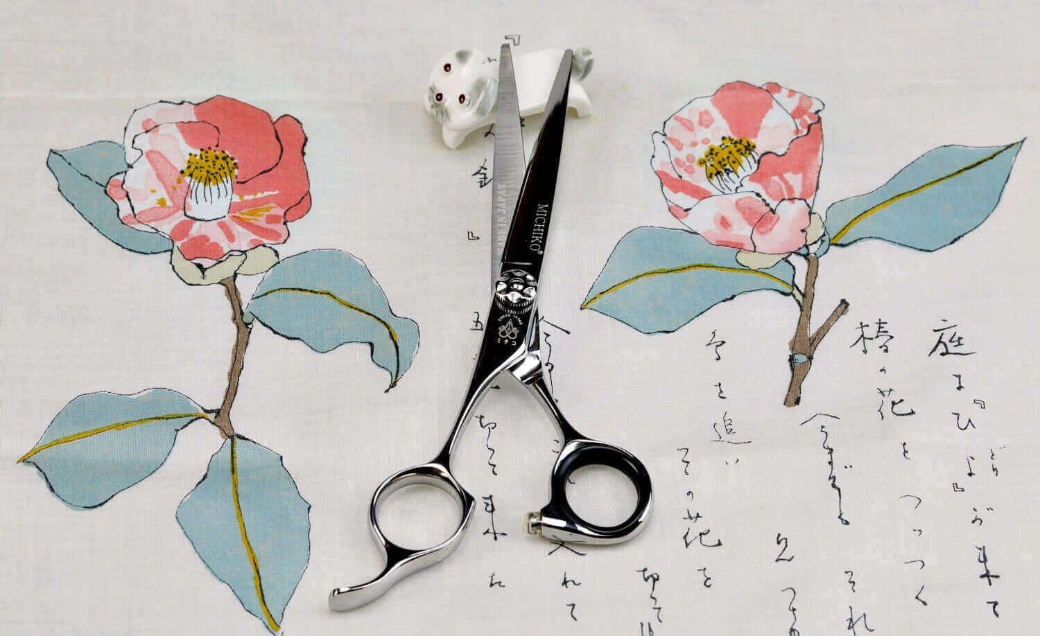 Premium left-handed hair cutting scissors by Michiko, displayed on Japanese floral fabric with calligraphy—ideal for professional stylists seeking ergonomic and stylish scissors.