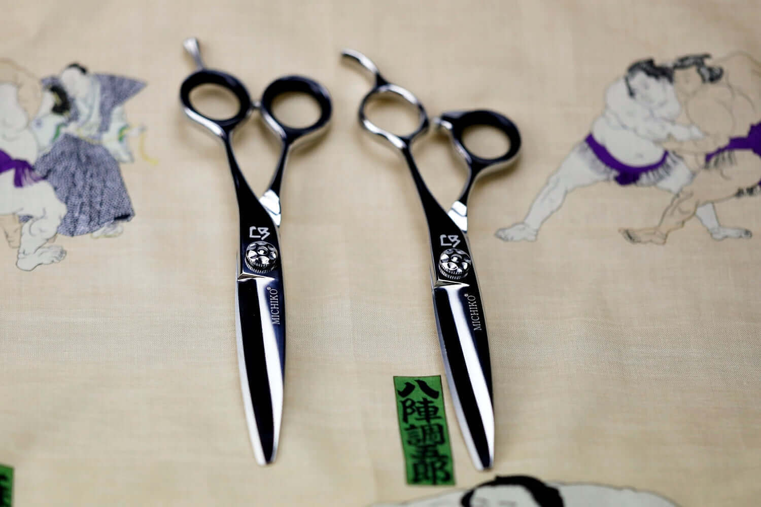 Two pair of slide hair cutting scissors on a traditional Japanese pattern fabric backgournd