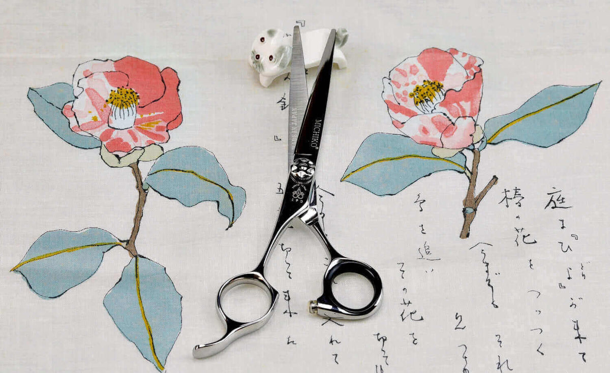 Premium left-handed hair cutting scissors by Michiko, displayed on Japanese floral fabric with calligraphy—ideal for professional stylists seeking ergonomic and stylish scissors.
