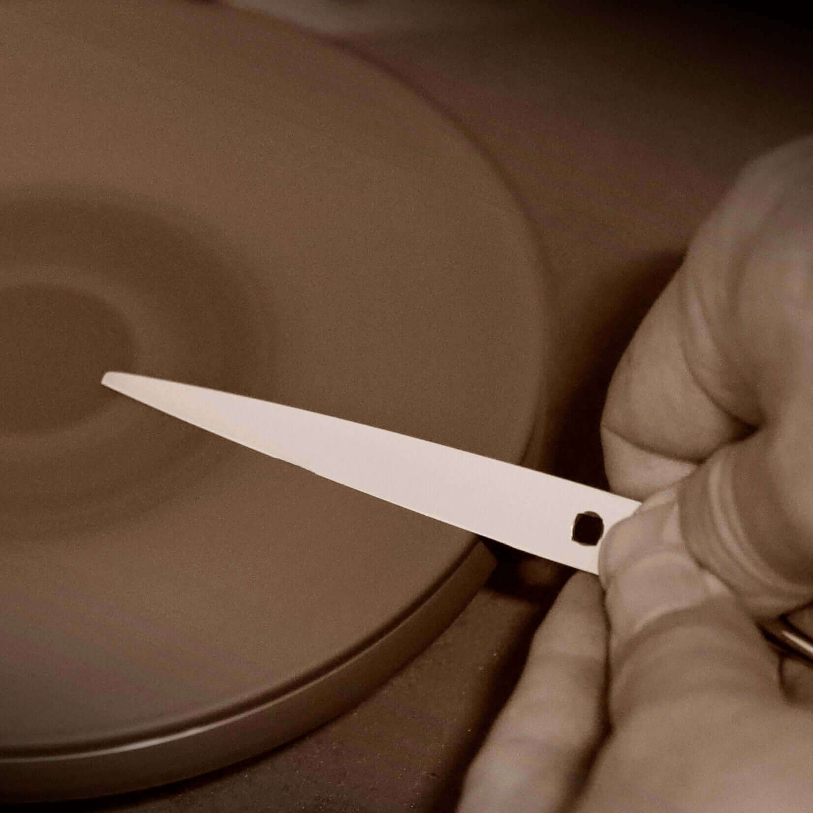 Professional sharpener honing a blade on a sharpening machine to achieve a precise convex edge.