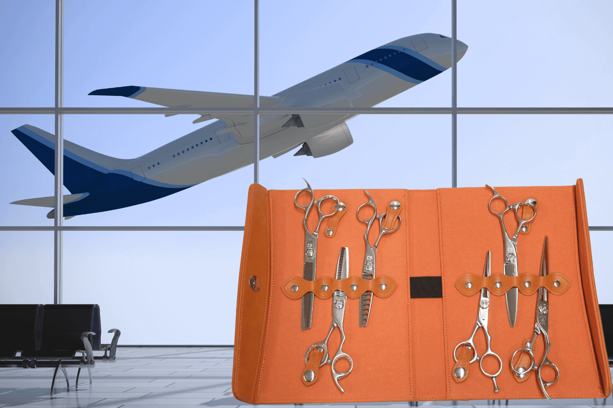Orange scissors case containing six pairs of barber scissors on a background of an airplane taking off outside an airport window