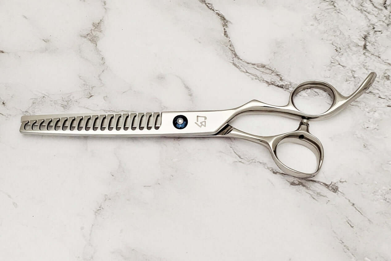 Barber texturizing shears on a marble surface.