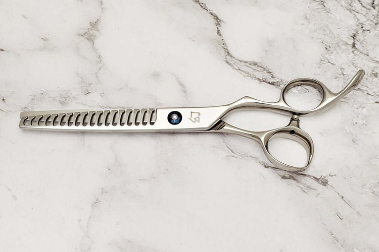 Barber texturizing shears on a marble surface.