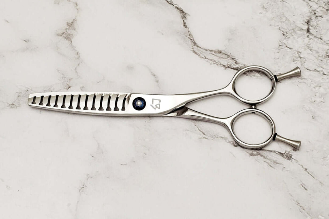 Double teeth hair texturizing shears on a marble surface