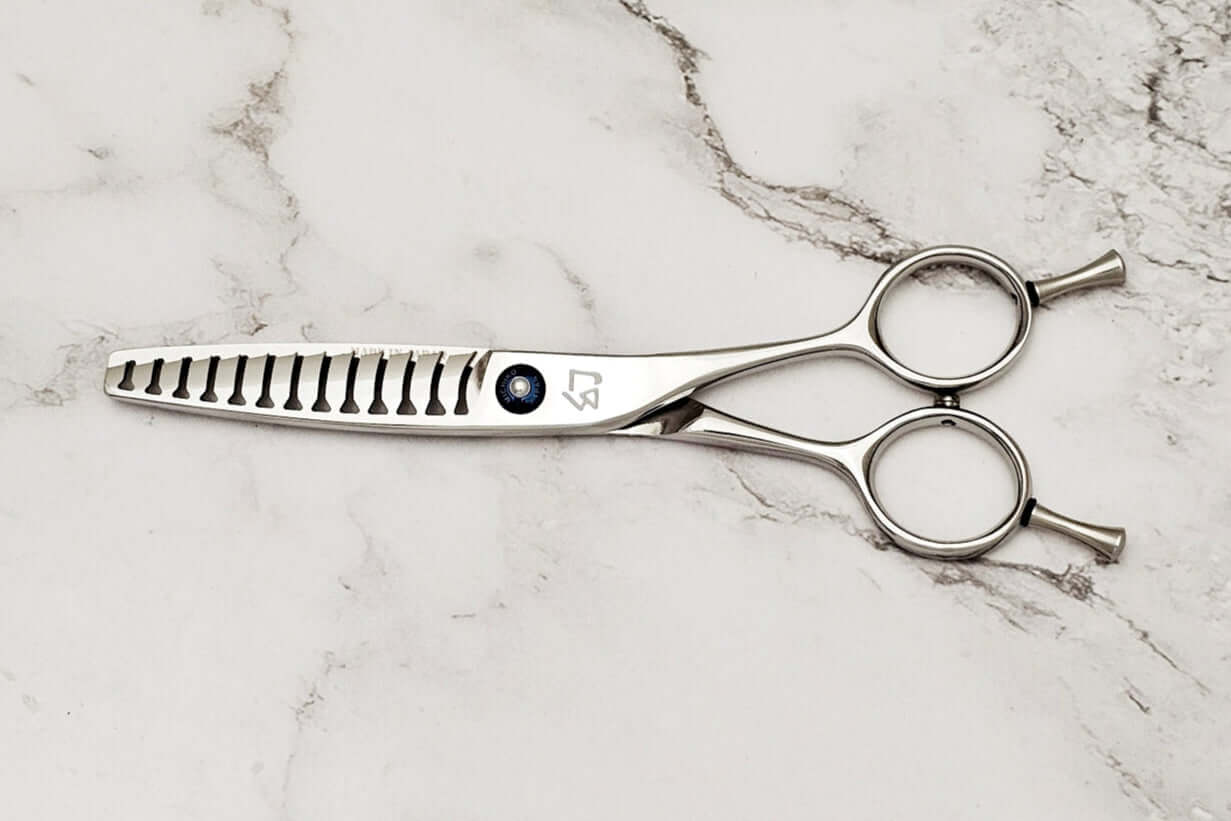 Double teeth hair texturizing shears on a marble surface