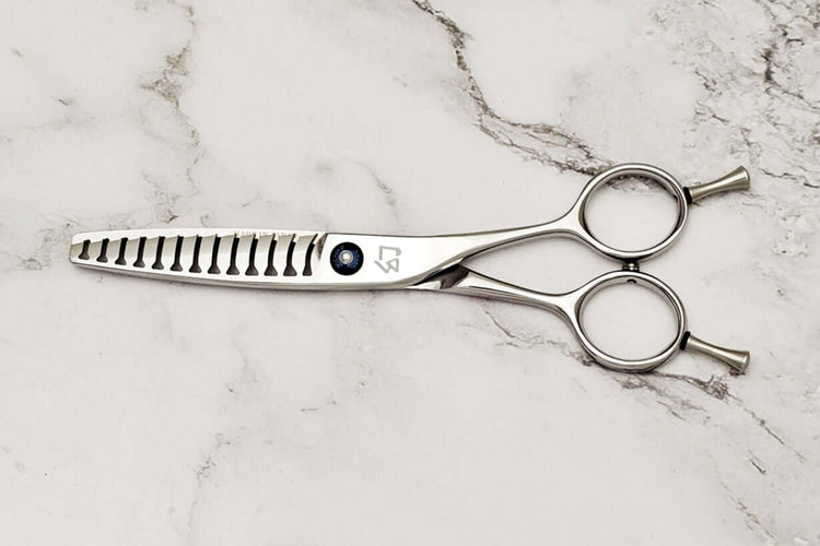 Double teeth hair texturizing shears on a marble surface