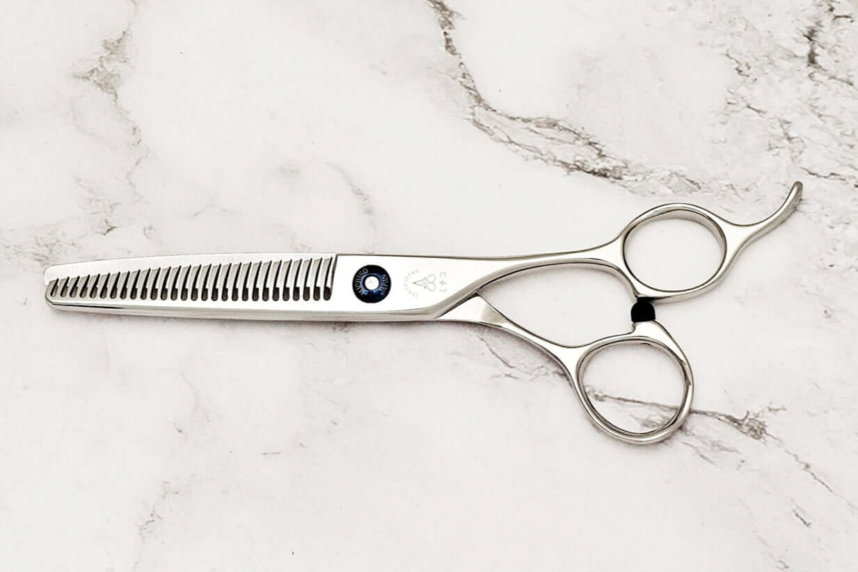 Pair of hair thinning scissors on a marble surface,