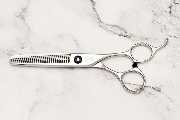 Pair of hair thinning scissors on a marble surface,