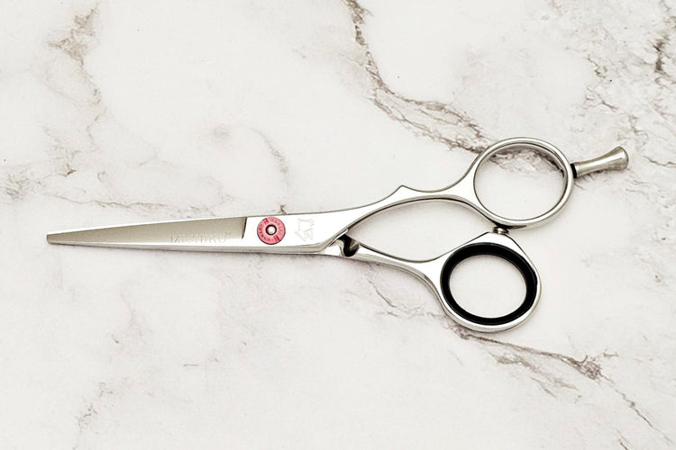 Precision hair cut scissors on white marble background