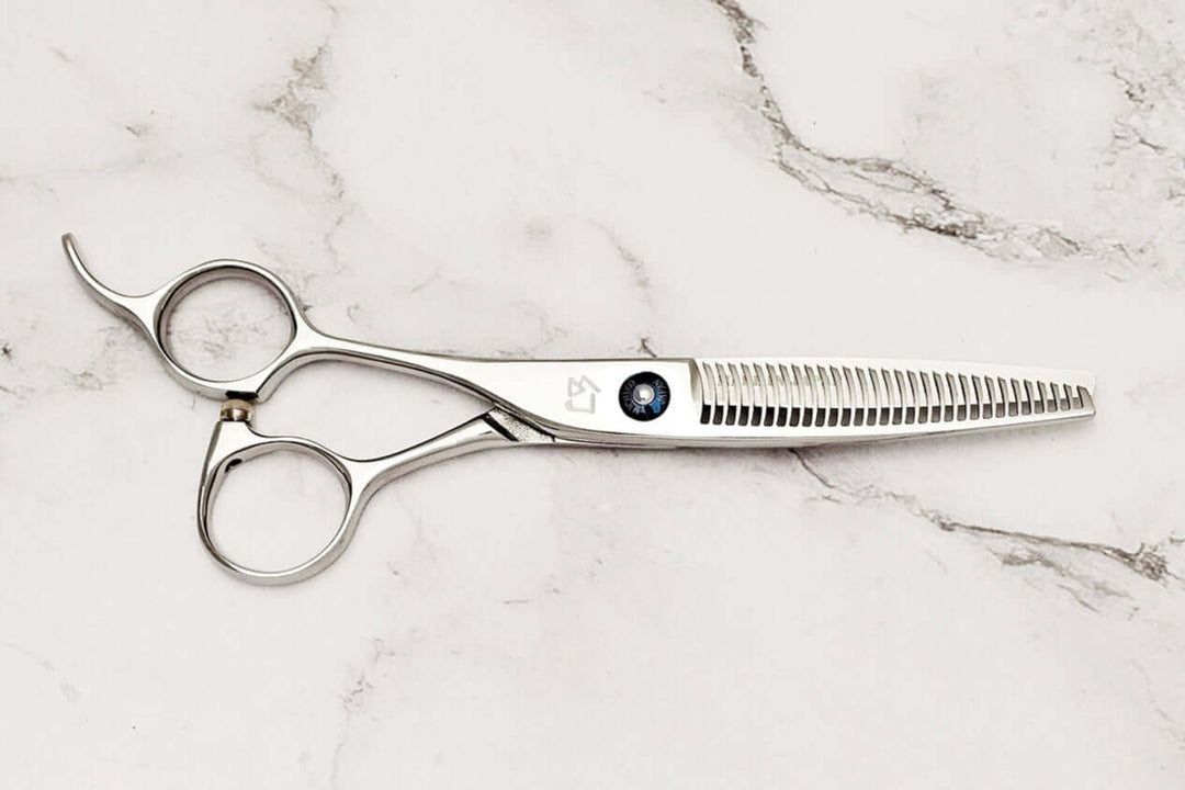 Left-handed hair-thinning scissors on a marble surface