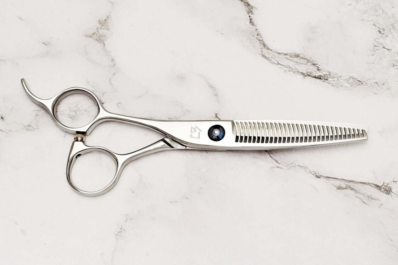 Left-handed hair-thinning scissors on a marble surface