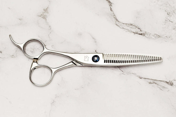 Left-handed hair-thinning scissors on a marble surface