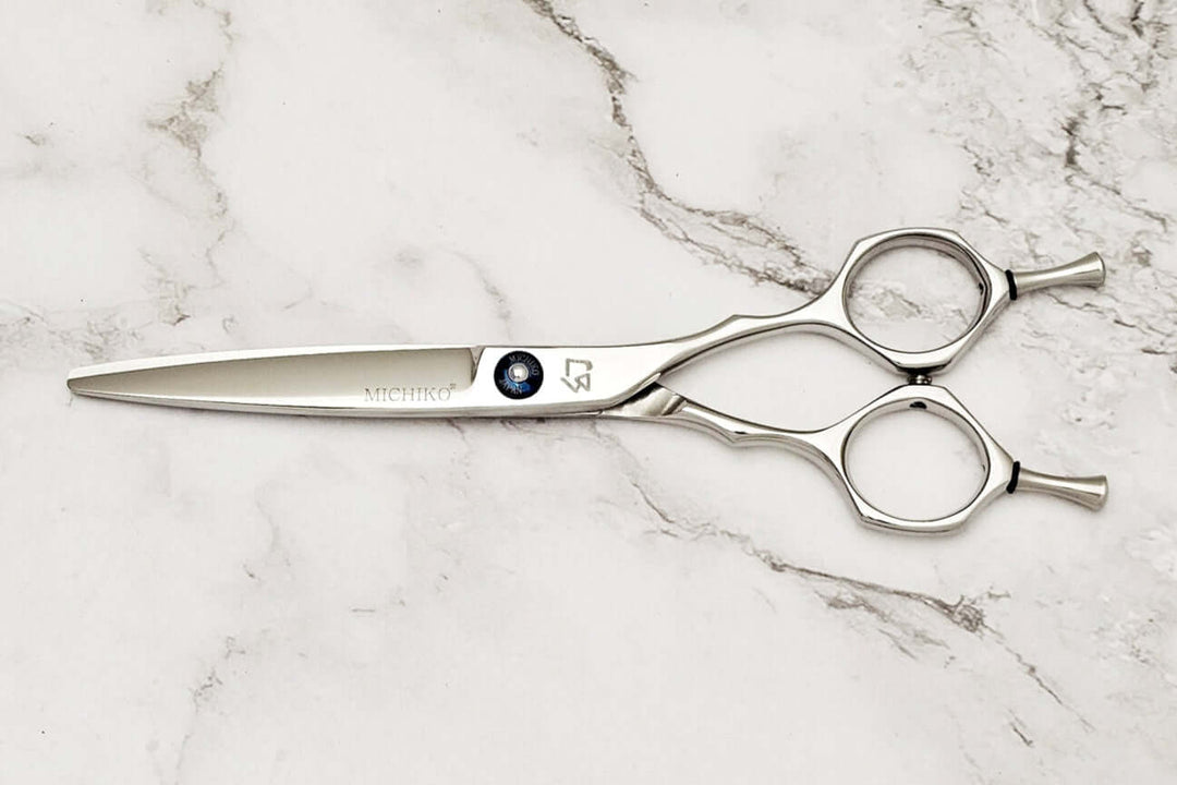 Hair scissors with a Michiko brand logo on a marble surface