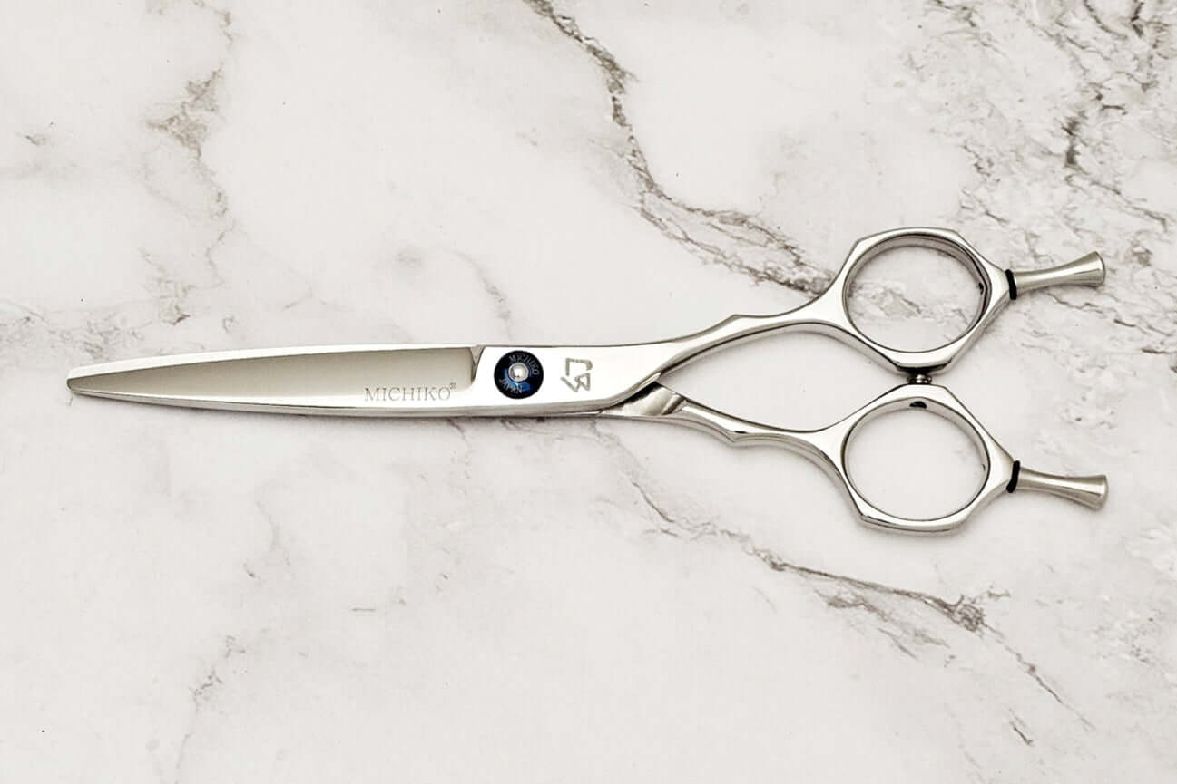 Hair scissors with a Michiko brand logo on a marble surface