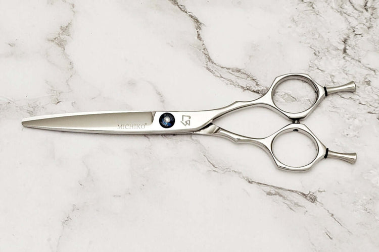Hair scissors with a Michiko brand logo on a marble surface