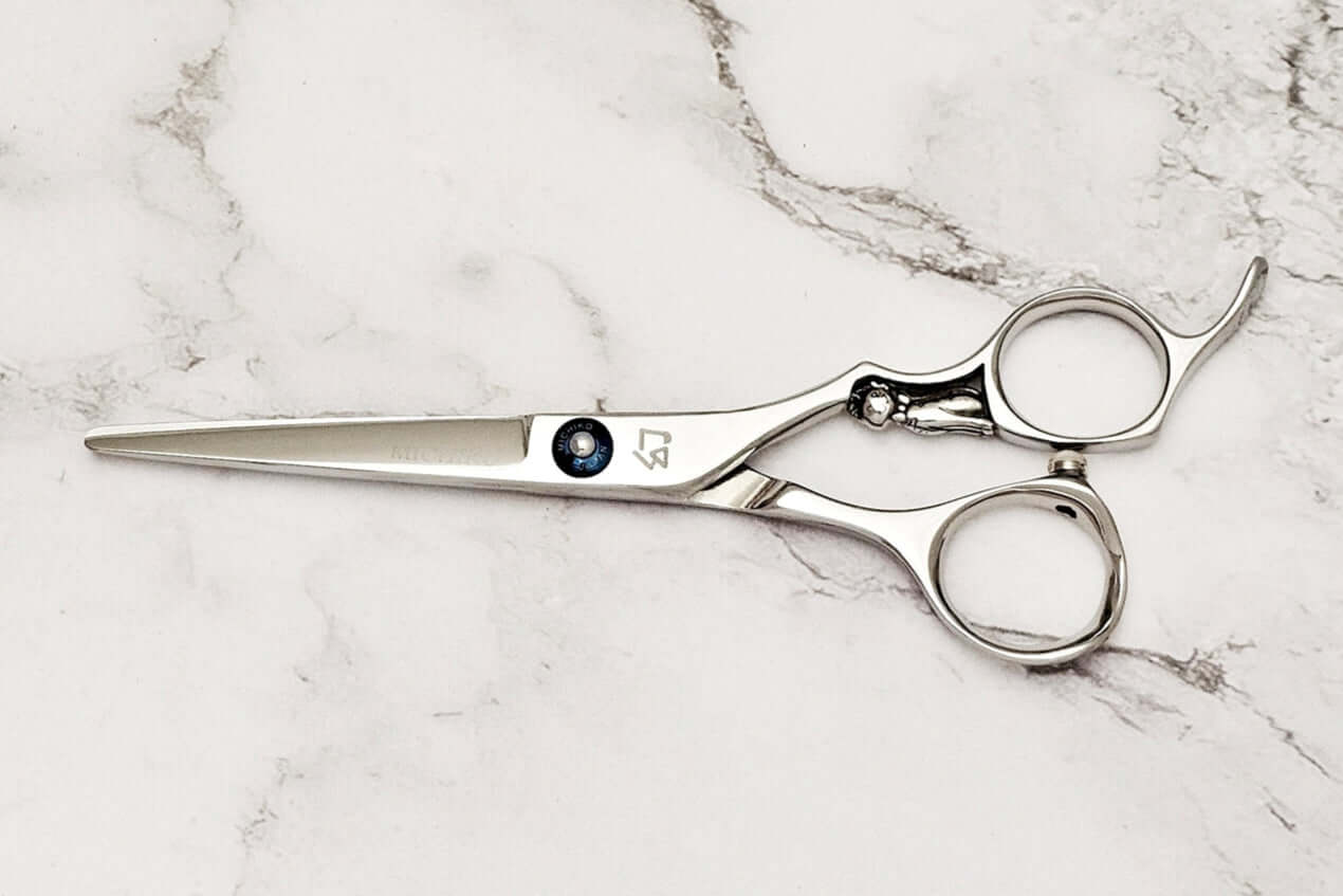 Pair of hair scissors on a marble surface