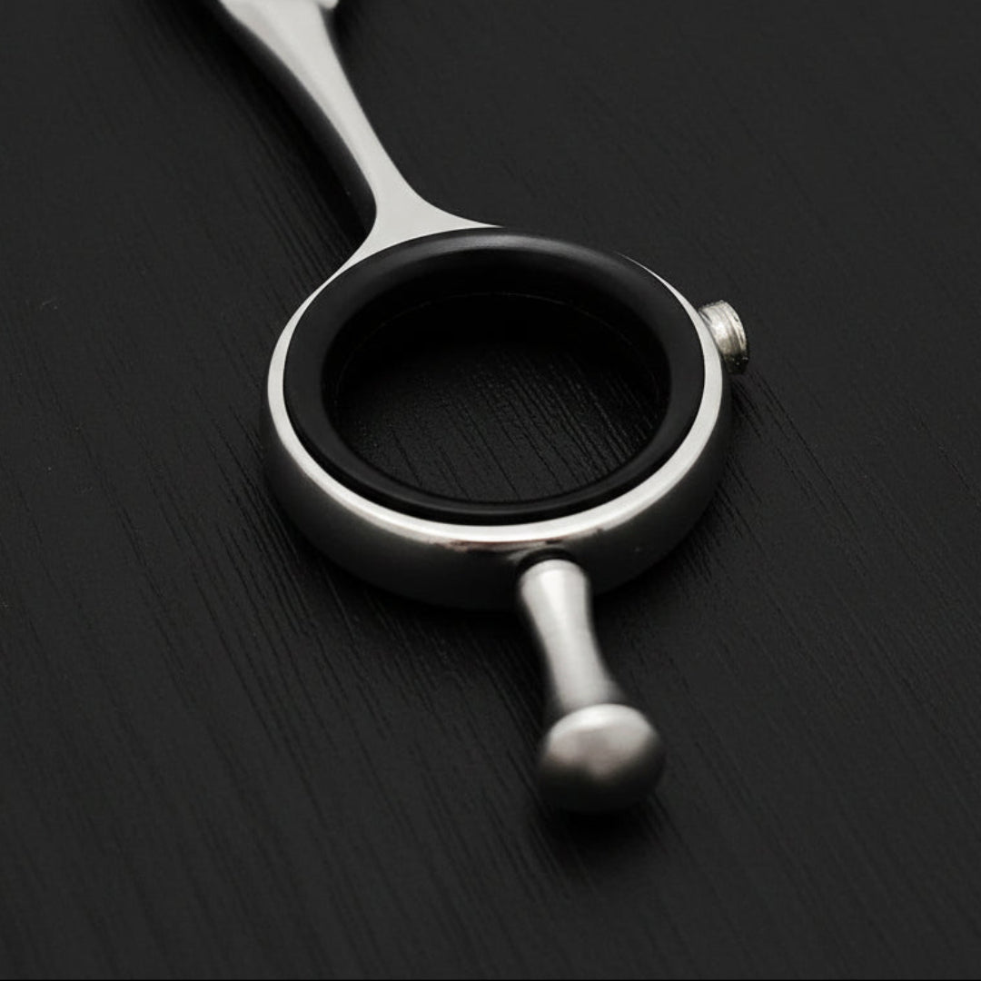 Close-up of a finger ring of hair cutting scissors on a white background