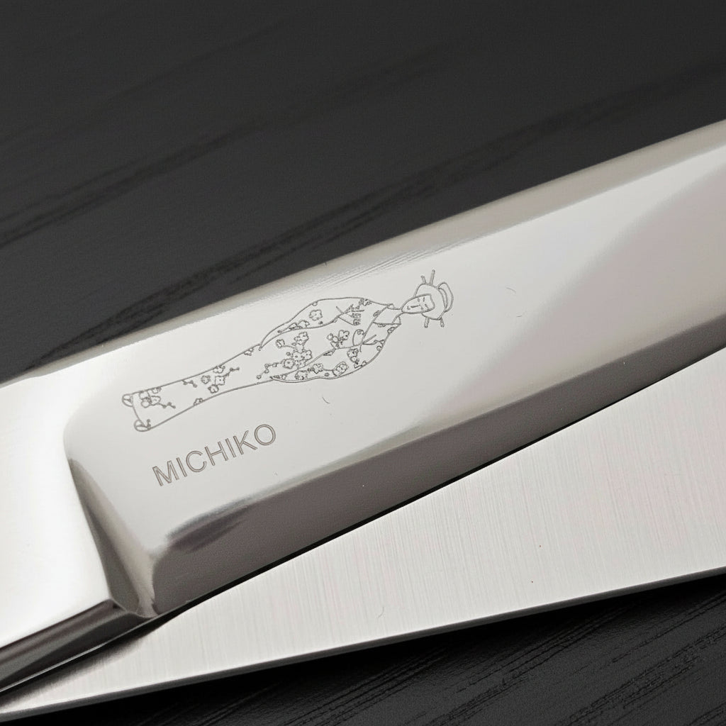 Close-up of a hair scissor blade with engraved Japanese lady wearing a kimono design on a white background