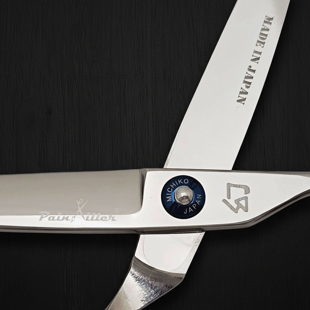 Close-up of a pair of scissors with 'Made in Japan' and brand logos on a white background