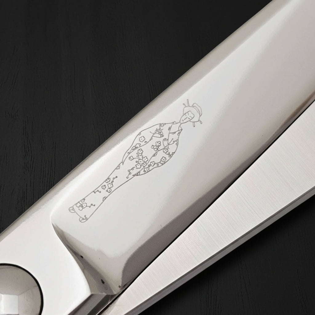 Close-up of a hair scissors blades with engraved Japanese lady wearing a kimono design on a white background