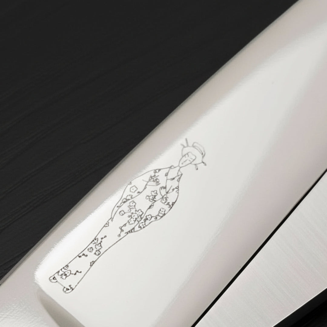 Close-up of a scissor blade with an engraved Japanese lady wearing a kimono design on a white background