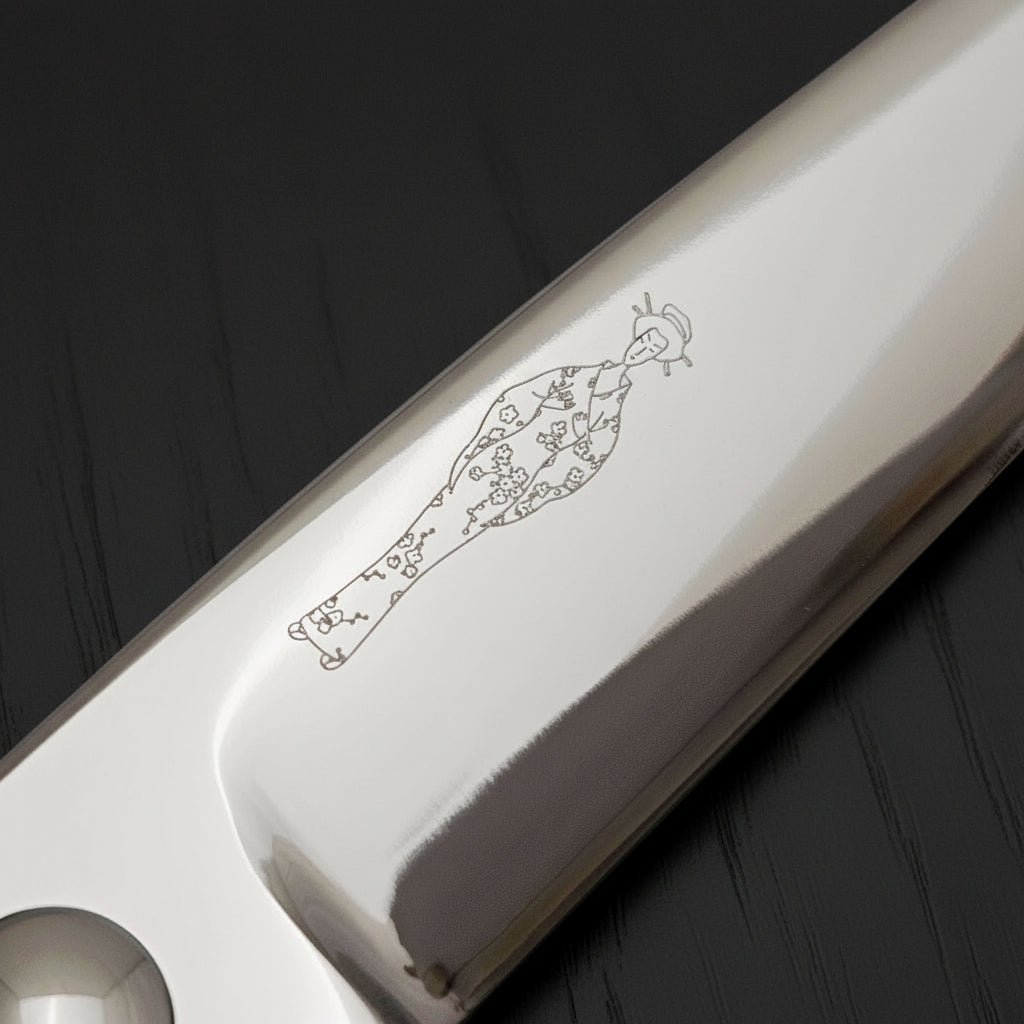 Close-up of a hair scissor blade with an engraved Japanese lady design on a white background