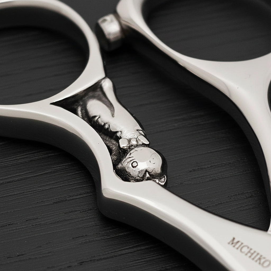 Close-up of an engraved kitten on a handle of hair shears on a white background
