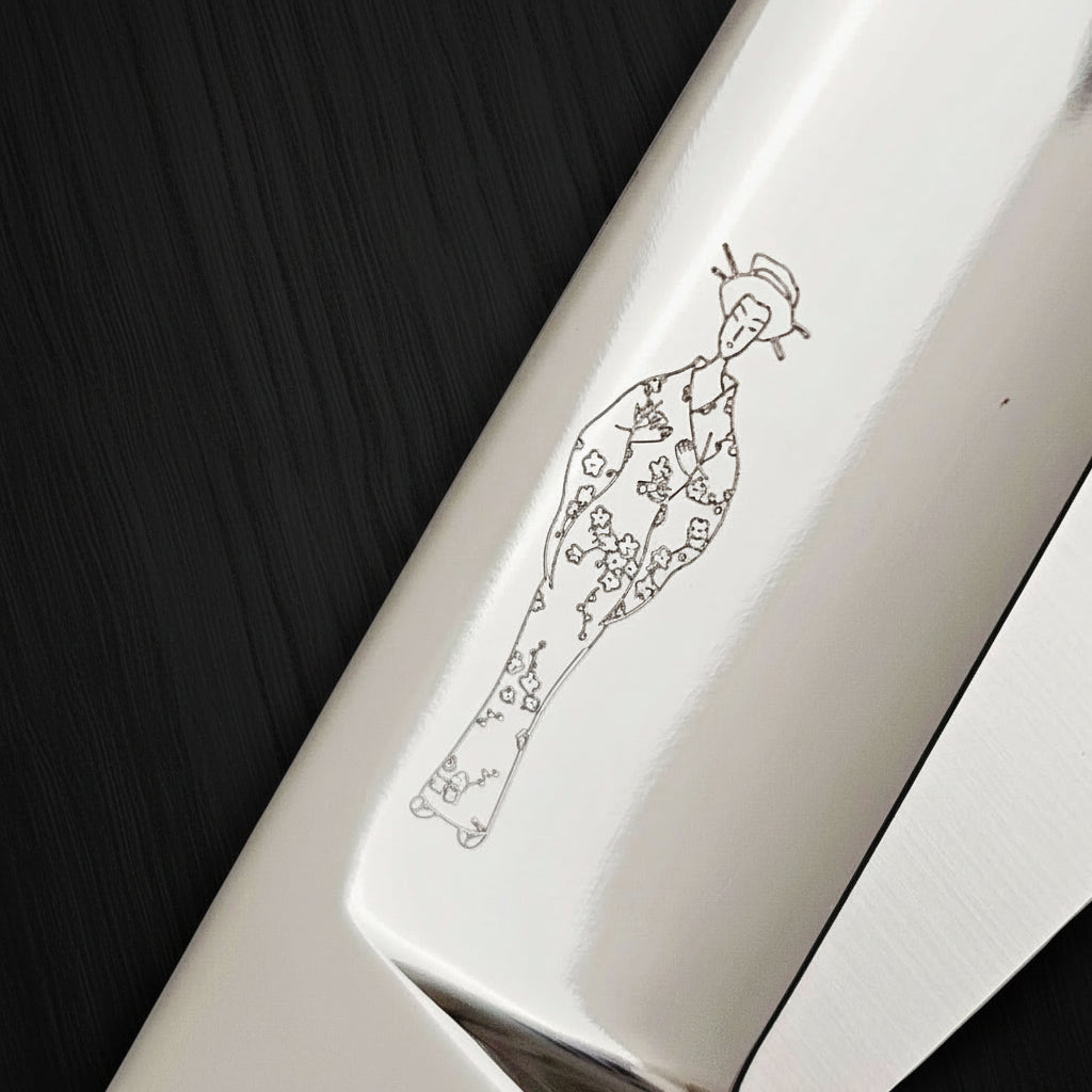 Close-up of a hair scissor blade with engraved Japanese ladey wearing a kimono design on a white background