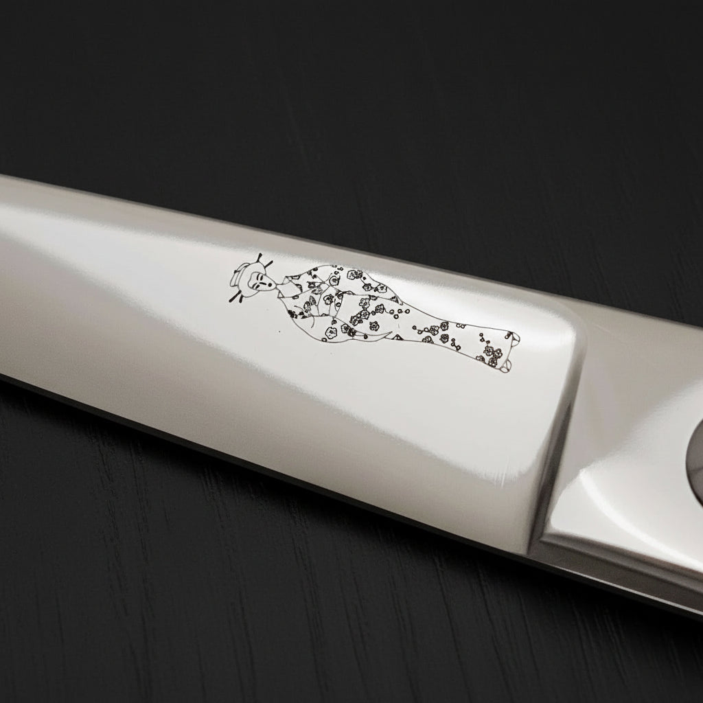 Close-up of a hair scissor blade with engraved Japanese lady wearing a kimono design on a white background