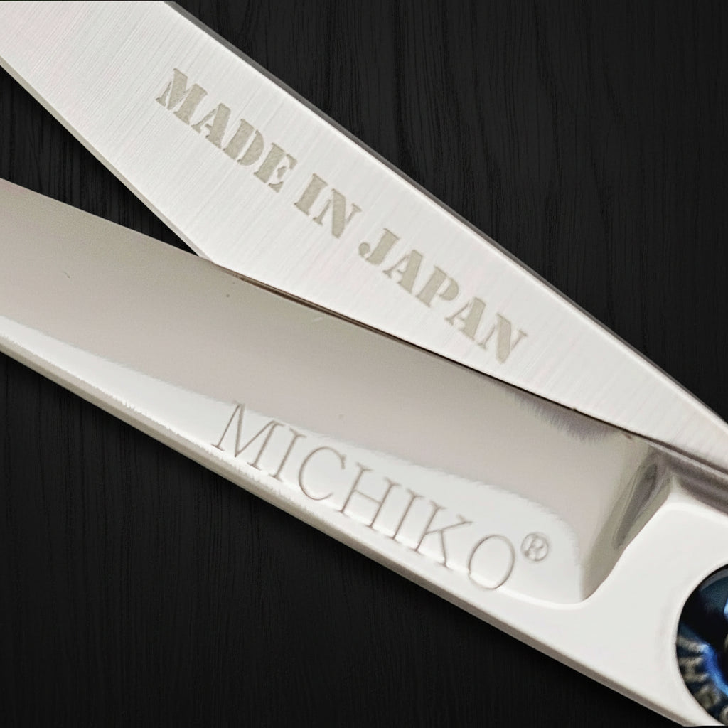 Close-up of hair scissors blades with 'MADE IN JAPAN' and 'MICHIKO' branding on a white background.