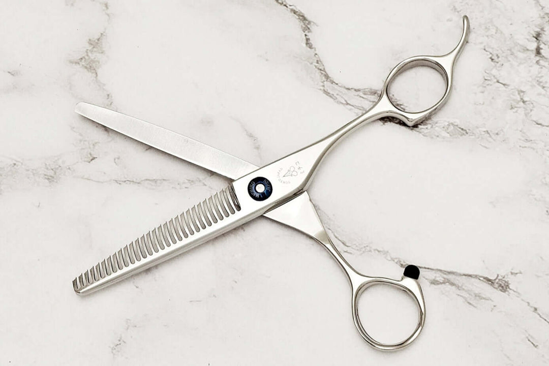 Pair of hair thinning scissors on a marble surface,