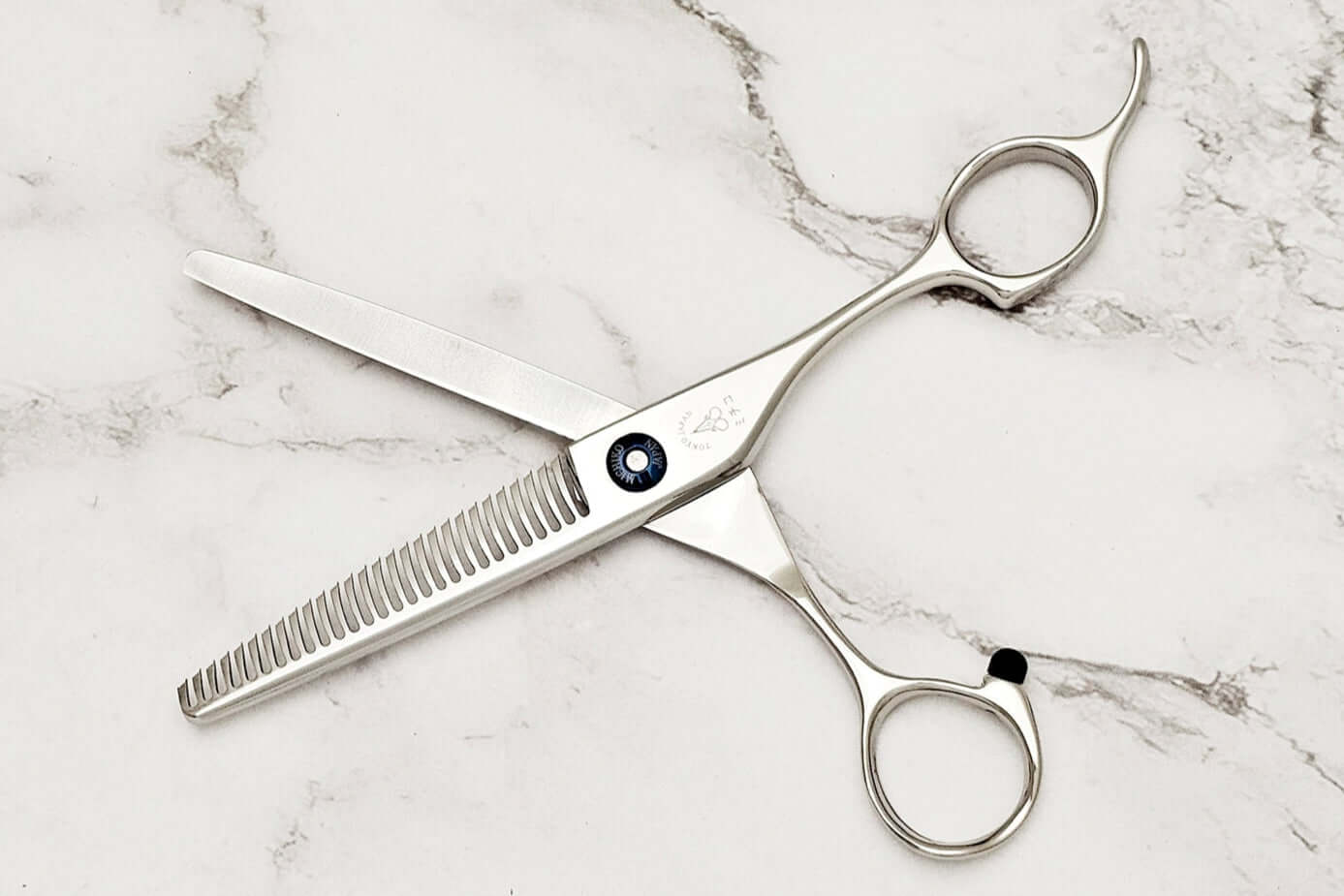 Pair of hair thinning scissors on a marble surface,