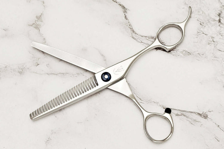 Pair of hair thinning scissors on a marble surface,