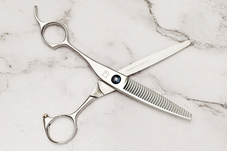 Left-handed hair-thinning scissors on a marble surface