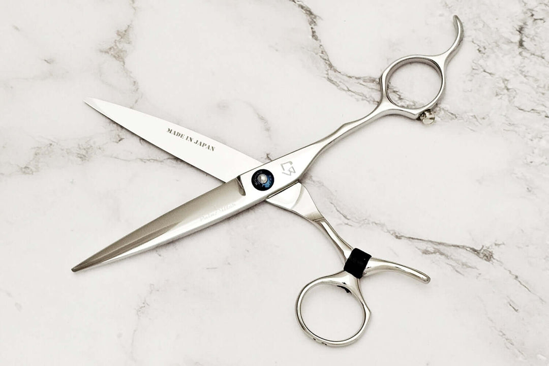 Pair of swivel hair scissors on a marble surface
