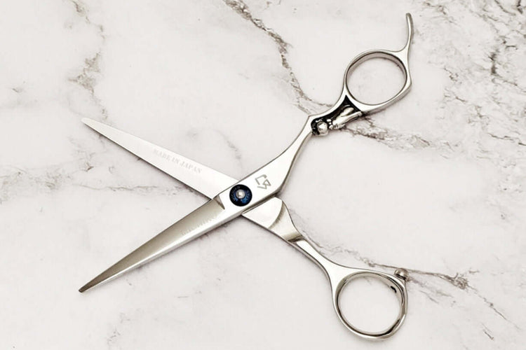 Pair of hair scissors on a marble surface